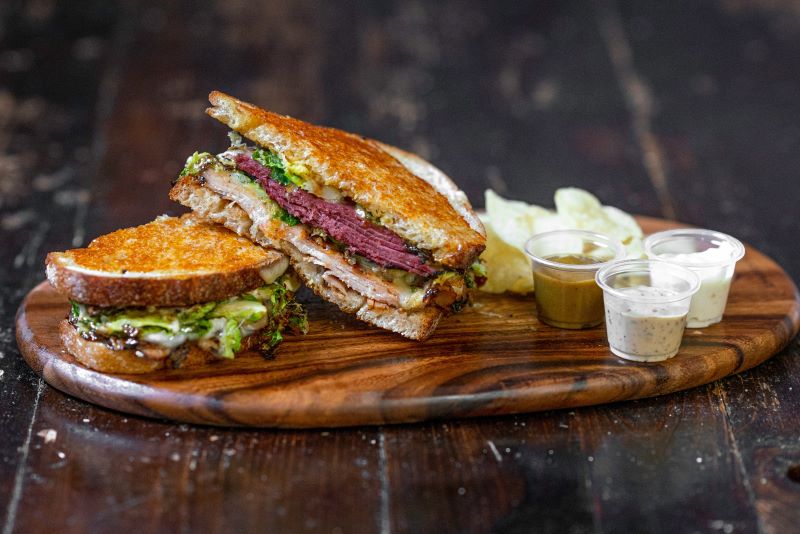 Grilled ham sandwich and dips on a wooden plate